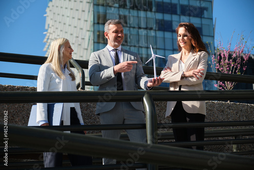 Obraz na płótnie Business team discussing renewable energy project with miniature wind turbine w salonie