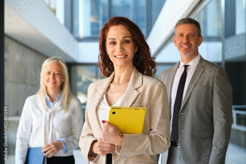Obraz na płótnie Business team smiling in modern office building holding tablet and documents w salonie