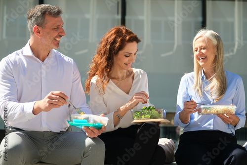 Obraz na płótnie Office workers enjoying their lunch break together, eating healthy meals from reusable containers, promoting sustainability and wellbeing w salonie