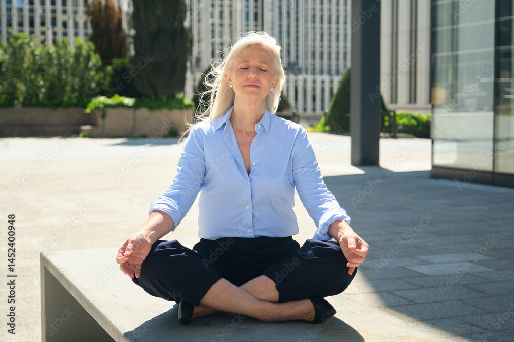 Mature businesswoman practicing yoga in the city during her work break, finding peace and balance