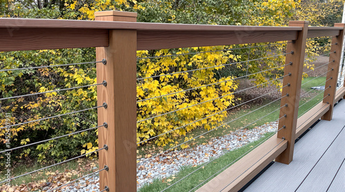 modern deck railing with stainless steel cables and brown wooden posts