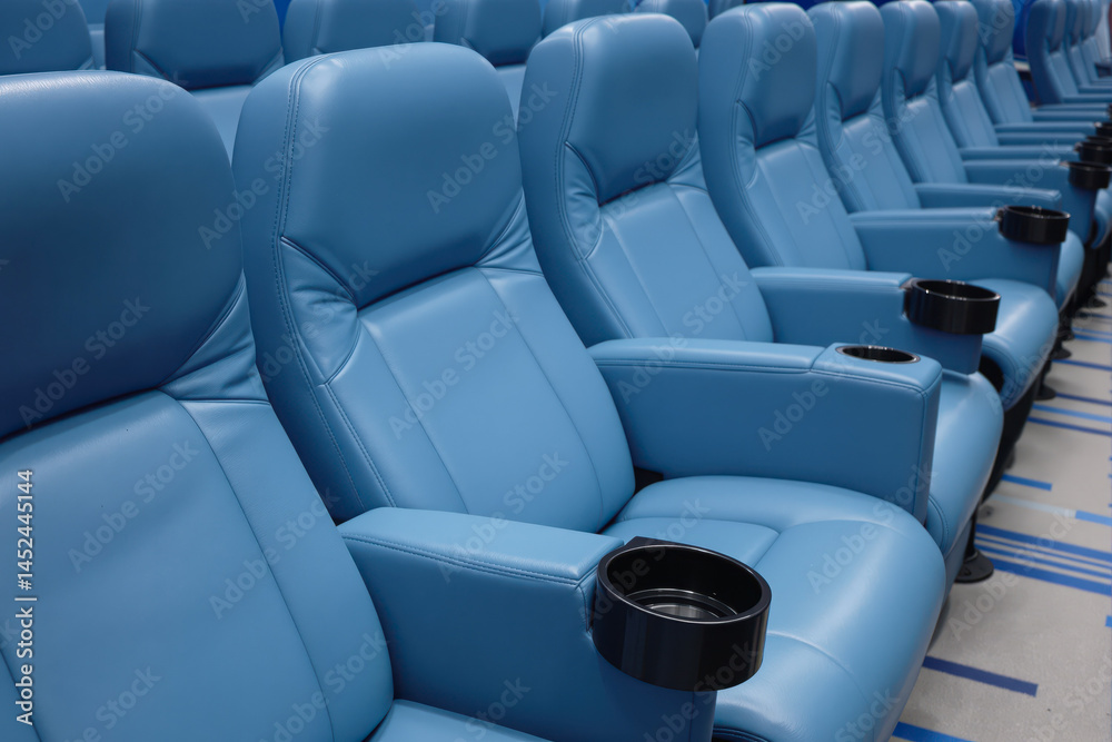 Fototapeta premium rows of comfortable powder-blue leather seats with built-in cup holders in a modern theater