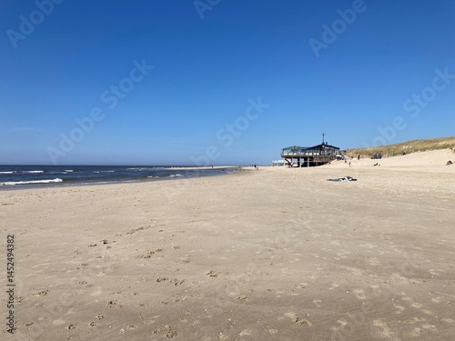 Weitläufiger Strand mit Dünen und Meer und Pfahlbau Restaurant unter blauem Himmel in Camperduin in Holland photo