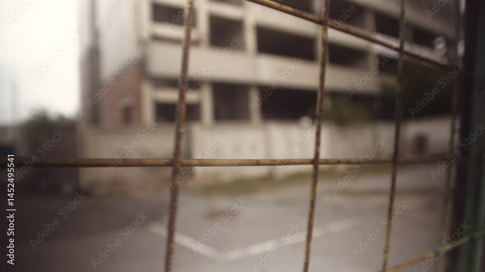Close-up of a fence mesh against the background of slums, a building under construction.