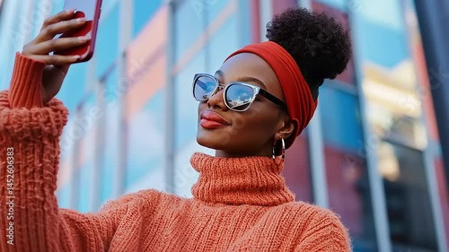 Young woman taking a selfie in a vibrant urban setting with colorful building reflections