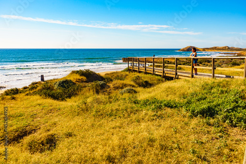 Woman walking on wooden path on sea shore