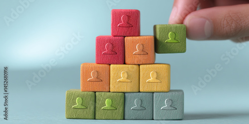 Colorful wooden blocks forming pyramid, each block showing person icon, symbolizing team building, growth, or human resources management
