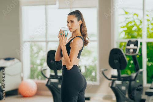 Young hispanic with energy drink woman workout at gym