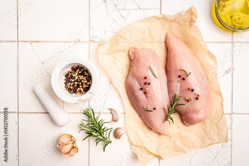Raw chicken fillet or breasts with ingredients for cooking on a paper, white background. Top view with copy space. High quality photo