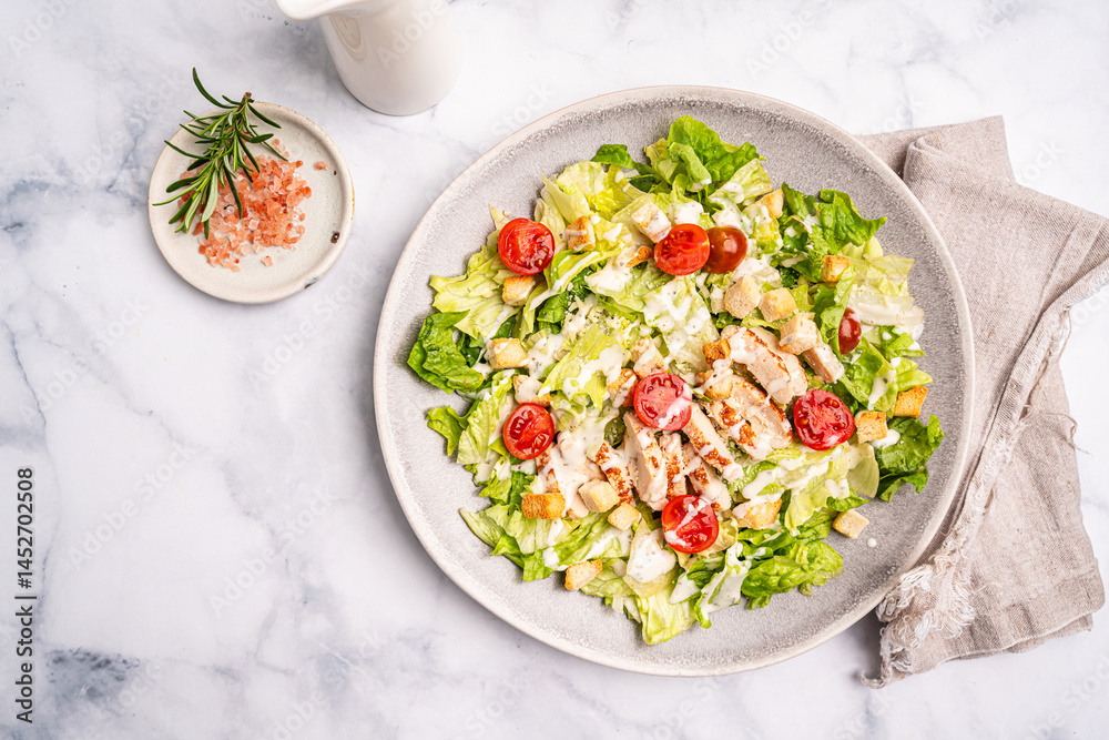 Fresh caesar salad with chicken breast, croutons, lettuce, parmesan cheese, sauce and tomatoes on white background, top view. High quality photo
