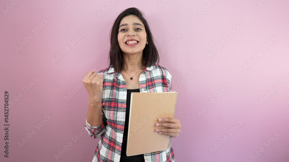 college girl holding book and doing 'yes!' hand gesture with pronouncing it with big happiness college girl holding book and doing 'yes!' hand gesture with pronouncing it with big happiness