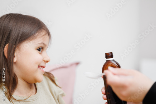 child is sick in bed. Mom gives cough syrup to her daughter. Concept disease, pharmaceutics.