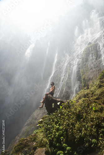 Chico sobre roca en cascada de Tumpak Sewu, Java, Indonesia