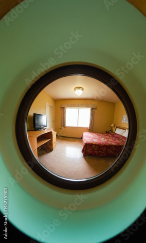 Obraz na płótnie Interior scene showing a bedroom through a round window, with furniture and decor visible w salonie