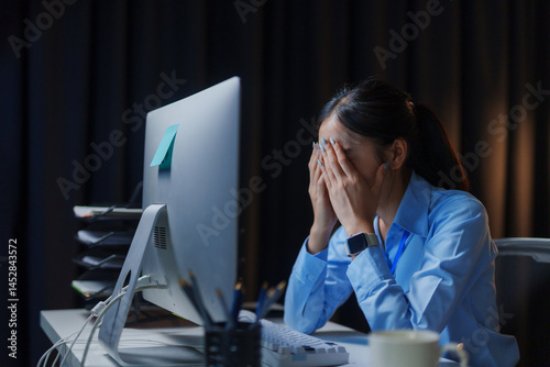 Exhausted office worker battling burnout and frustration while laboring late into the night, surrounded by the glow of screens and paperwork