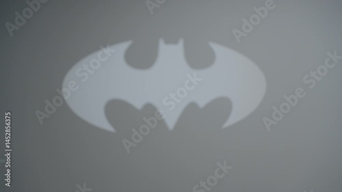 Bat symbol projected on a wall, showcasing iconic imagery in a dimly lit space during evening hours