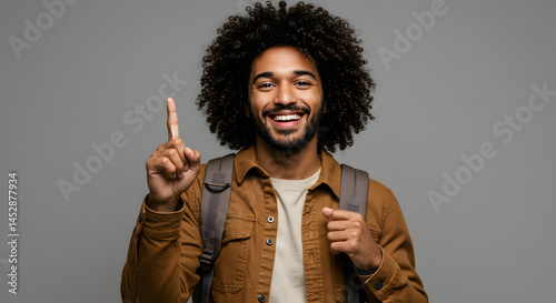 Obraz na płótnie Smiling young man with curly hair showing one finger in studio w salonie