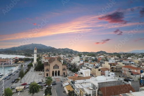 Fototapeta Naklejka Na Ścianę i Meble -  Breathe in the beauty of Zakynthos Town as the sun sets, casting warm hues over bustling streets, traditional architecture, and the serene waters of the Ionian Sea