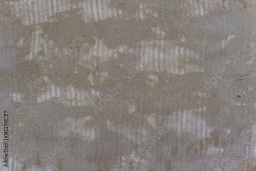 A grey wall with a white mesh pattern. The mesh is in the shape of squares.