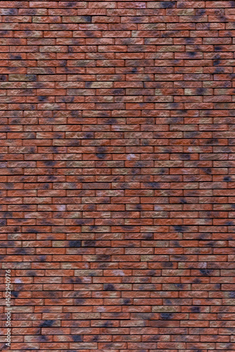 A brick wall with a brown and tan color. The wall is made of bricks. The bricks are arranged in a pattern.