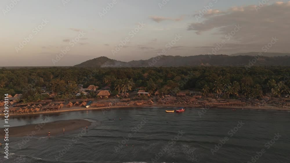 Vista Aérea al Atardecer en la Playa Tropical: Cabañas Rústicas, Palmeras y Botes en la Orilla