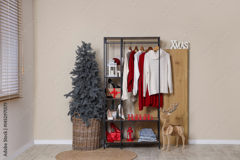 Obraz premium Clothes rack with shoes and Christmas tree near beige wall in dressing room