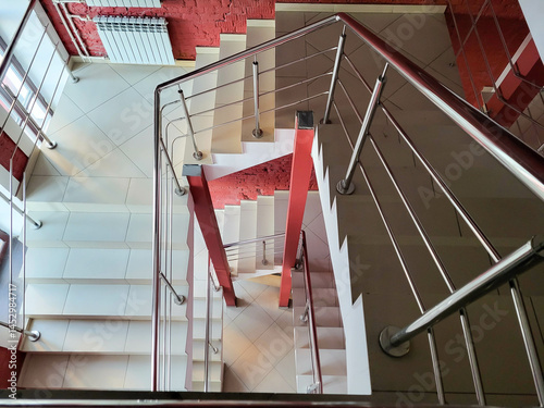 A flight of stairs with red walls, looking down when viewed from above