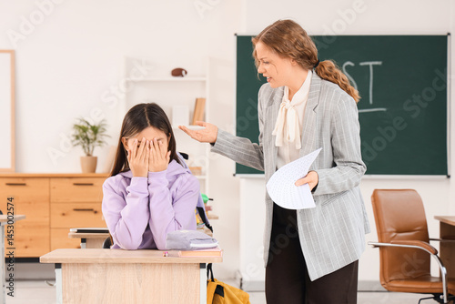 Obraz na płótnie Female teacher scolding teenage girl for bad grade in classroom