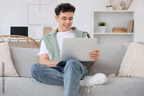Young man working with laptop on sofa at home