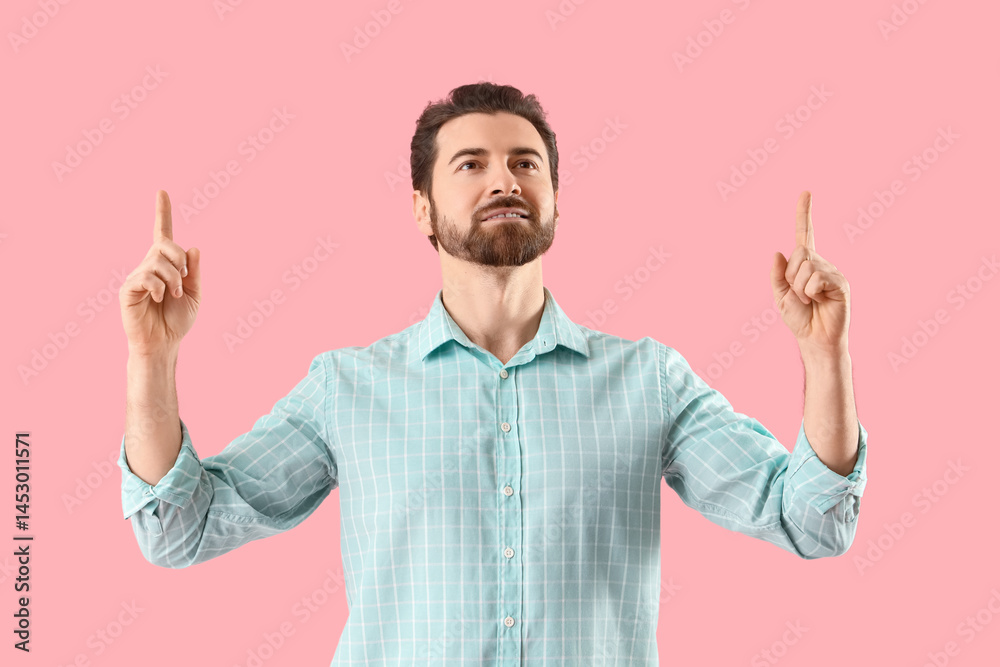 Handsome man pointing at something on pink background Handsome man pointing at something on pink background