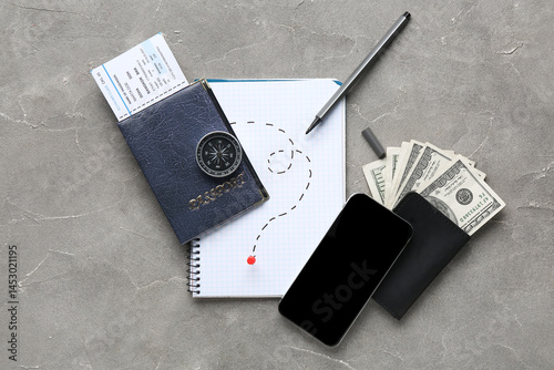 Notebook with drawn route, compass, blank mobile phone and money on grunge background. Itinerary concept