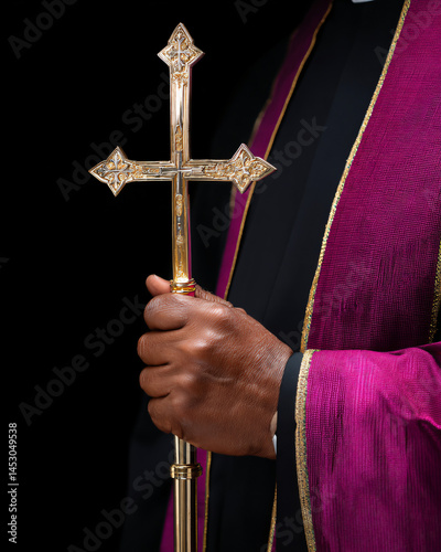 black bishop holding golden crosier during sacred ceremony, hand detail on liturgical staff with embedded cross symbol photo