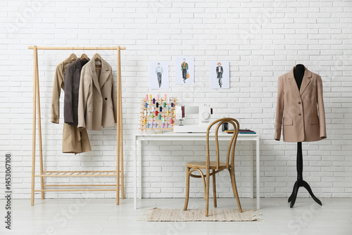 Tailor's workplace with clothes rack and mannequin near white brick wall in atelier
