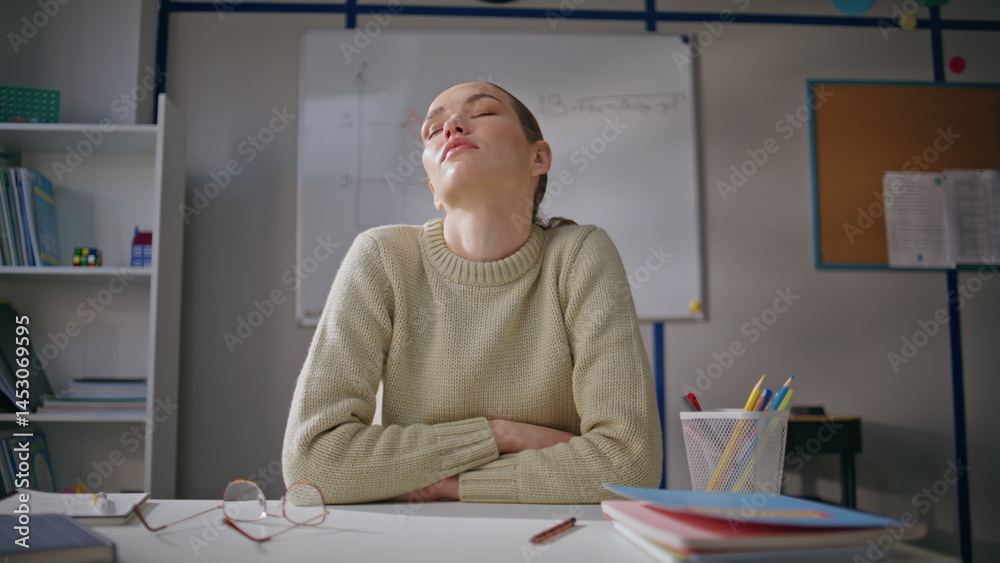 Tired teacher stretching shoulders at class room closeup. Woman taking break