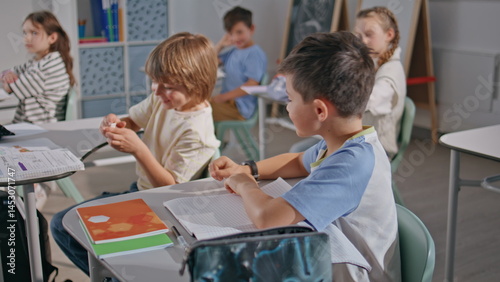 Obraz na płótnie Boy giving note classmate at cozy class room. Funny pupils kids communicating w salonie