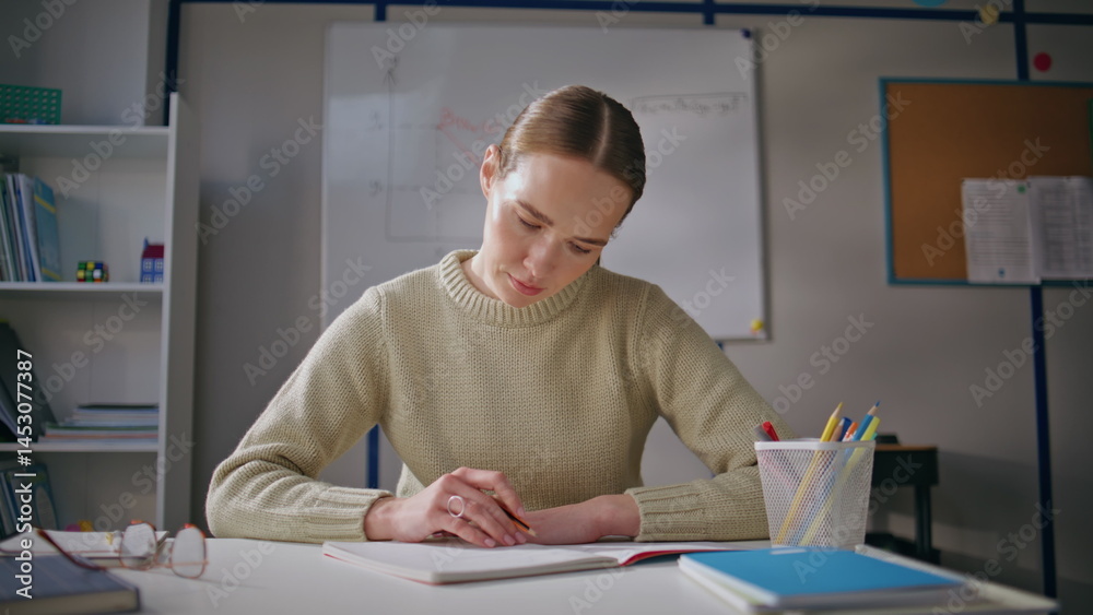 Attentive teacher checking homework working school at class room alone closeup
