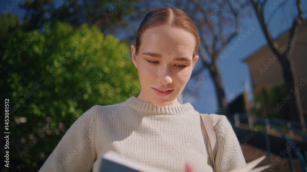 Happy woman flipping book standing in front green trees closeup. Teacher reading