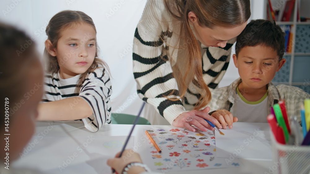 Art teacher helping kids in classroom closeup. Children having drawing class