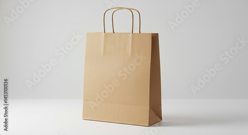 A simple brown paper shopping bag with handles standing on a white surface in studio lighting