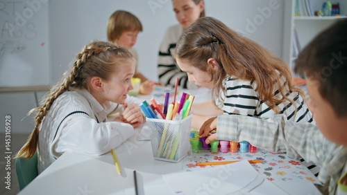 Obraz na płótnie Two girls drawing pictures at big school table closeup. Inspired kids talking w salonie