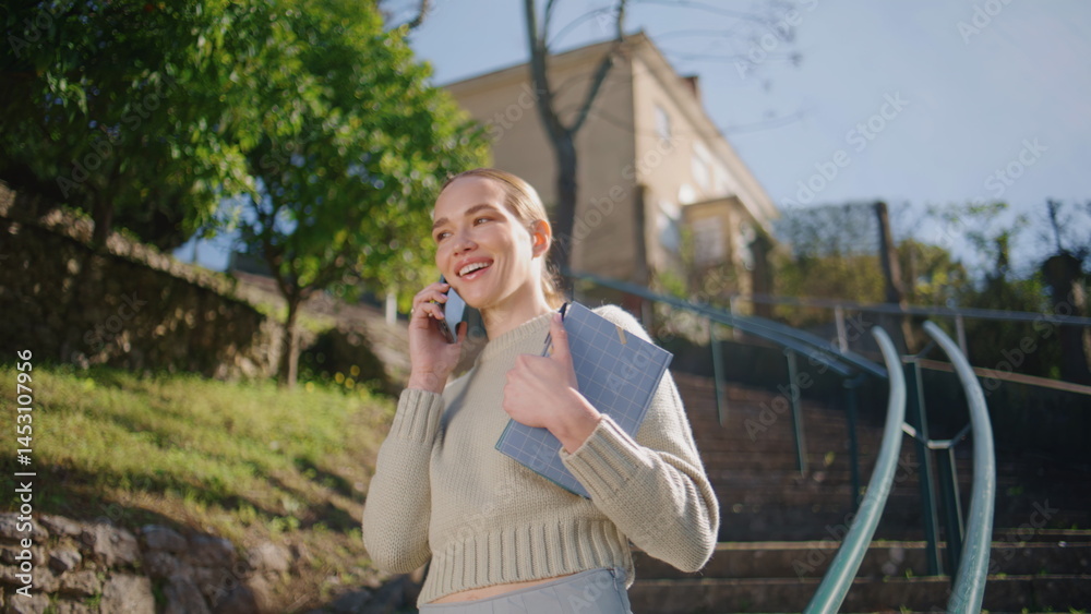 Cheerful model talking cellphone at sunlight park closeup. Student strolling