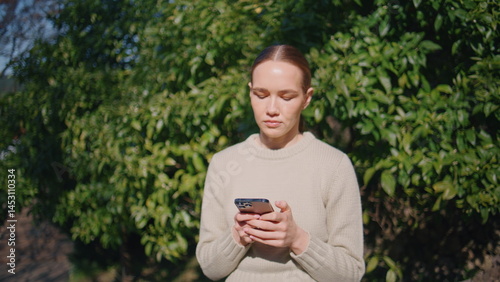 Worried girl using smartphone standing sunny city closeup. Lady typing message