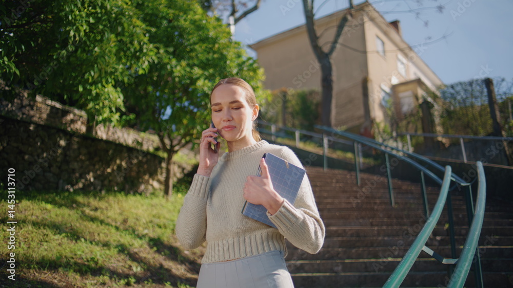 Smiling woman talking mobile phone call sharing good news at sunny park closeup