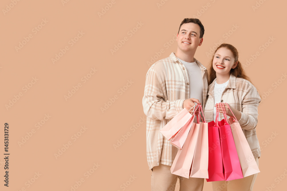 Beautiful young couple with shopping bags on brown background Beautiful young couple with shopping bags on brown background