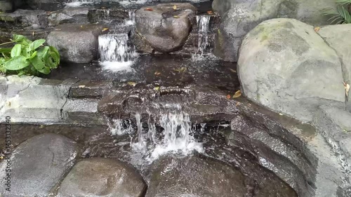 Experience serenity as water gently cascades over sculpted stone steps, forming a tranquil, natural waterfall. A textured backdrop that provides a calming scene.