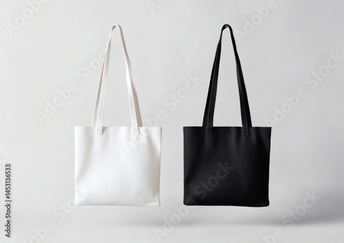 Two plain tote bags, one black and one white, are displayed side by side on a neutral gray background,

 photo