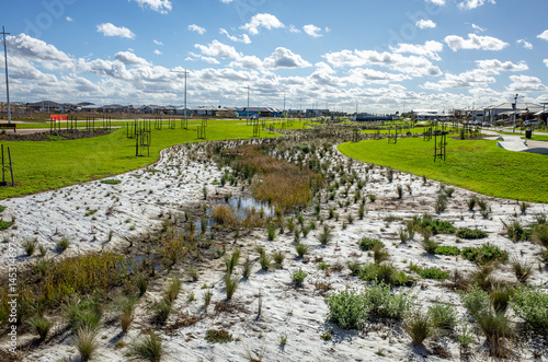 Newly planted stormwater management reserve in an Australian suburban estate--themes of sustainable urban drainage, green infrastructure, and ecological landscaping in residential developments. photo