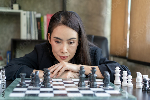 A woman is playing chess and is looking at the board
