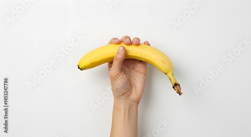 A hand firmly holding a banana upright against a plain white background. Concept image for strength, health, and nutrition. photo