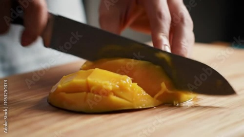 Person slicing a yellow bun with a knife on a wooden cutting board in a close up food preparation shot